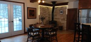 a dining room with a table and a wood stove at Le Iris in Saint-Alexis-des-Monts