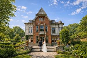 a bride and groom standing in front of a mansion at Le Manoir des Etangs in Etbos