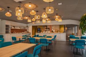 a restaurant with blue chairs and tables and chandeliers at Sure Hotel by Best Western Nantes Saint-Herblain in Saint-Herblain