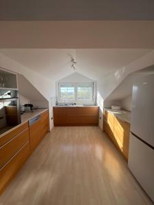 an attic kitchen with wooden cabinets and a window at Helles, großzügiges Loft mit Fernblick in Siegendorf im Burgenland