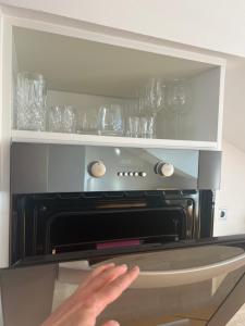 a person is reaching into an open oven at Helles, großzügiges Loft mit Fernblick in Siegendorf im Burgenland