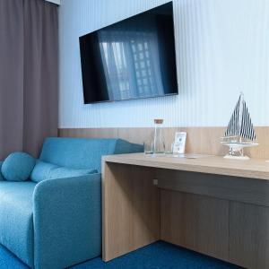 a living room with a blue couch and a desk at Marina Apartamenty ChKŻ in Charzykowy