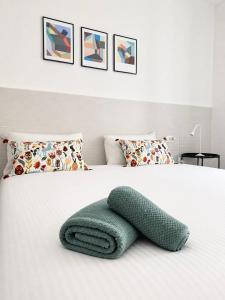 a green blanket on a white bed with pillows at Dietro le Quinte Rho Apartments in Rho +10 photos