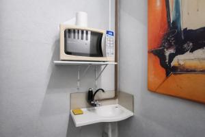 a bathroom with a sink and a tv on a wall at Solar Clefis in Vitória
