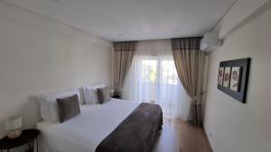 a bedroom with a white bed and a window at Thouse Fontainhas in Cascais