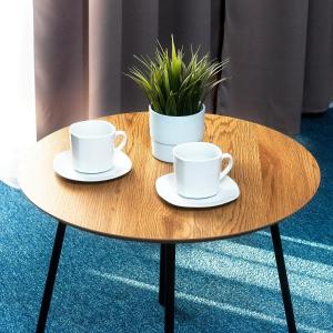 two cups and saucers on a wooden table with a plant at Marina Apartamenty ChKŻ in Charzykowy