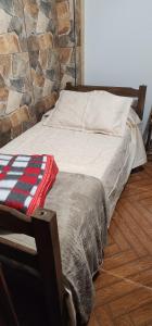 a bed in a room with a stone wall at La Quimera a pasos de la playa in Atlántida