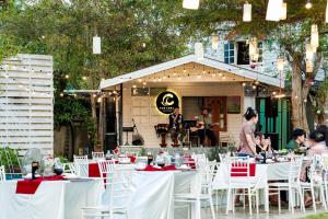 a group of white tables and chairs with red napkins at The Canal Ratchaburi in Ratchaburi