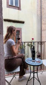 a woman sitting on a chair drinking a glass of wine at Regnos Altos boutique rooms in Bosa