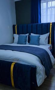 two beds with blue and yellow pillows in a room at CB Luxury in Kisii