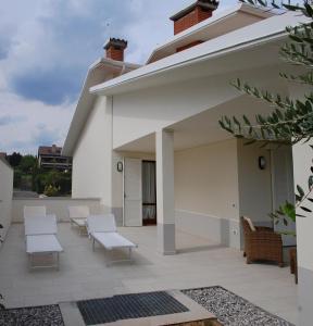 un patio con sillas blancas y un edificio en Villa Sophora, en Moniga del Garda