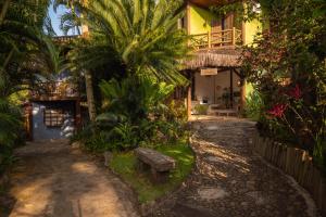 a courtyard of a house with palm trees and a bench at Pousada Villaggio Assis in Ilhabela