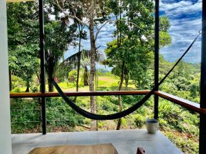a hammock in a room with a view of a forest at Tierra Encantada in Dominicalito +2 photos
