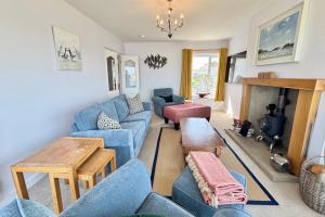 a living room with blue couches and a fireplace at AEL-Y-BRYN-5 BED- DRAMATIC SEA VIEWS - Sleeps 12 in Trearddur