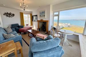 a living room with blue furniture and a view of the ocean at AEL-Y-BRYN-5 BED- DRAMATIC SEA VIEWS - Sleeps 12 in Trearddur