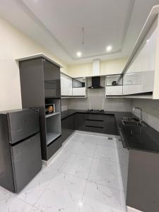 a kitchen with white cabinets and black appliances at premium category 2 bedrooms apartment in Lahore