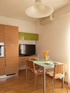 a kitchen with a table with chairs and a television at Apartment near Lake Como -300m to station -AC in Valmadrera +13 photos