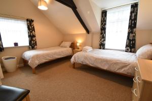 two beds in a room with two windows at Kingfisher in Whitland