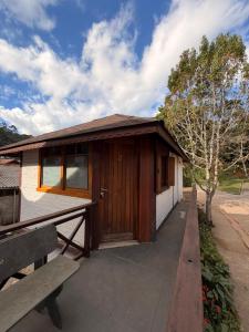 a small wooden building with a bench in front of it at Chales Vale da Nascente in Monte Verde