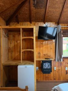 a room with a tv and a refrigerator in a cabin at Chales Vale da Nascente in Monte Verde