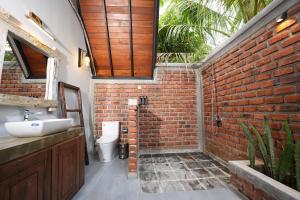 a bathroom with a brick wall and a sink at Aalanga Escape by Lush Villa in Kanugala