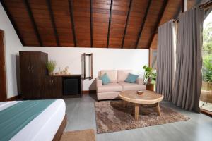 a bedroom with a bed and a couch and a table at Aalanga Escape by Lush Villa in Kanugala