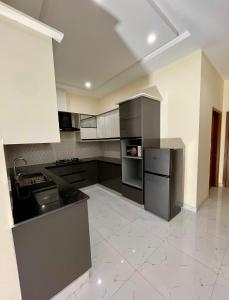 a large kitchen with black appliances and white tile floors at The Grand Avora Apartment With 3 Ac And Free Parking in Lahore