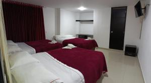 a hotel room with three beds with red sheets at Hotel the Blue House in Ipiales
