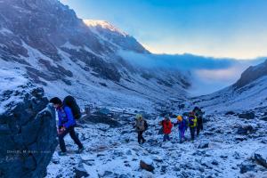 a group of people walking up a snow covered mountain at Atlas Rooftop Imlil in Imlil
