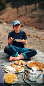a woman sitting on a table with a plate of food at Atlas Rooftop Imlil in Imlil