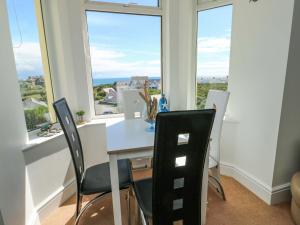 a dining room with a table and chairs and windows at Ewyn Y Don in Holyhead