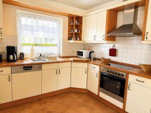 a kitchen with white cabinets and a stove top oven at Ferienhaus SOL - in Staphel