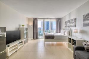 a white bedroom with a bed and a tv at MIAMI Collins Beach Apartments in Sunny Isles Beach