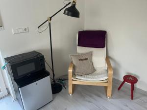 a room with a chair and a tv and a lamp at De Groene Oase in Harkstede