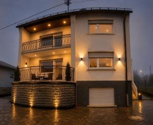 a white house with a balcony on a flooded street at Ferienwohnung Maison Maurus nahe Idar-Oberstein in Mörschied