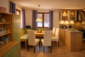 a kitchen with a wooden table and white chairs at Horner Viehweid in Schwangau