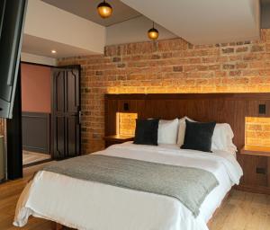 a bedroom with a large bed with a brick wall at 5Q House Chapinero in Bogotá