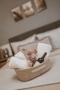 a basket of towels and a bottle of wine on a bed at Apartman Ivano in Vukovar
