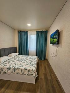 a bedroom with a bed with blue curtains and a television at Sun Estate Ureki in Ureki