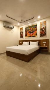 a bedroom with a large bed with paintings on the wall at Magnet Hotel in Vijayawāda