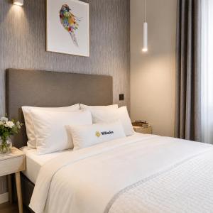 a bedroom with a large white bed with white pillows at Apartamenty Turystyczne WillkasSen in Giżycko
