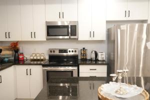 a kitchen with white cabinets and a stove and microwave at Charming Oakville Getaway in Oakville