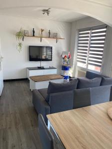 a living room with two blue couches and a tv at Maison cosy Dunkerque in Dunkerque
