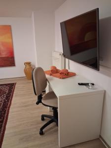 a room with a desk with a television and a chair at Neanderland-Apartment in Wülfrath