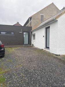 a house with a car parked in a driveway at Petite maison village fruitier in Gingelom