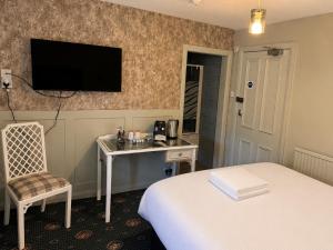 a hotel room with a bed and a desk and a television at Holland Hotel in Llanfachraeth +22 photos