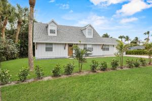 a white house with palm trees and a yard at Deck + Pool Table! Walk to Dtwn Jensen Beach in Jensen Beach
