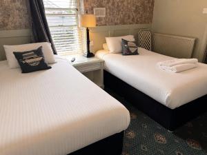 two beds sitting in a room with a window at Holland Hotel in Llanfachraeth
