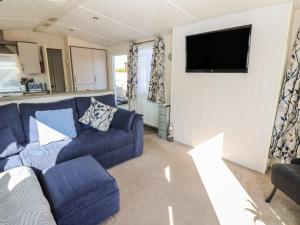 a living room with a blue couch and a tv at Plot 42 in Carlisle