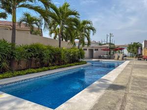 a swimming pool with palm trees next to a building at Nice and Modern Apartment, Parking in SamborondÃ³n